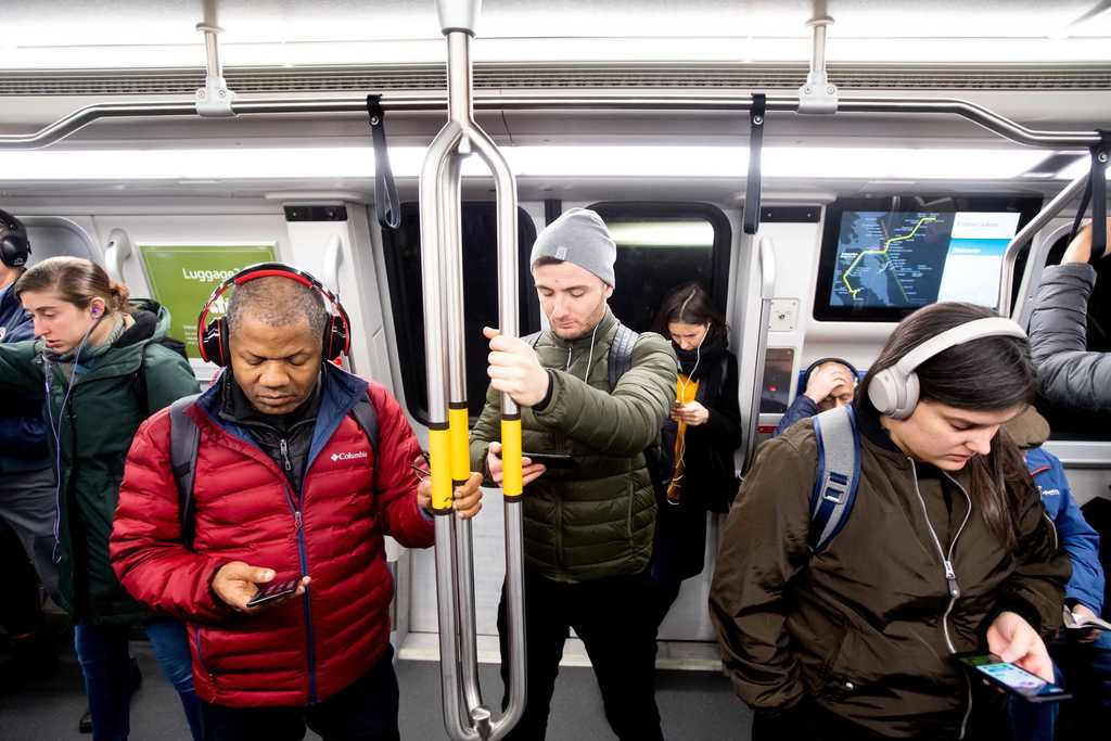 Riders onboard a Fleet of the Future train looking at their phones