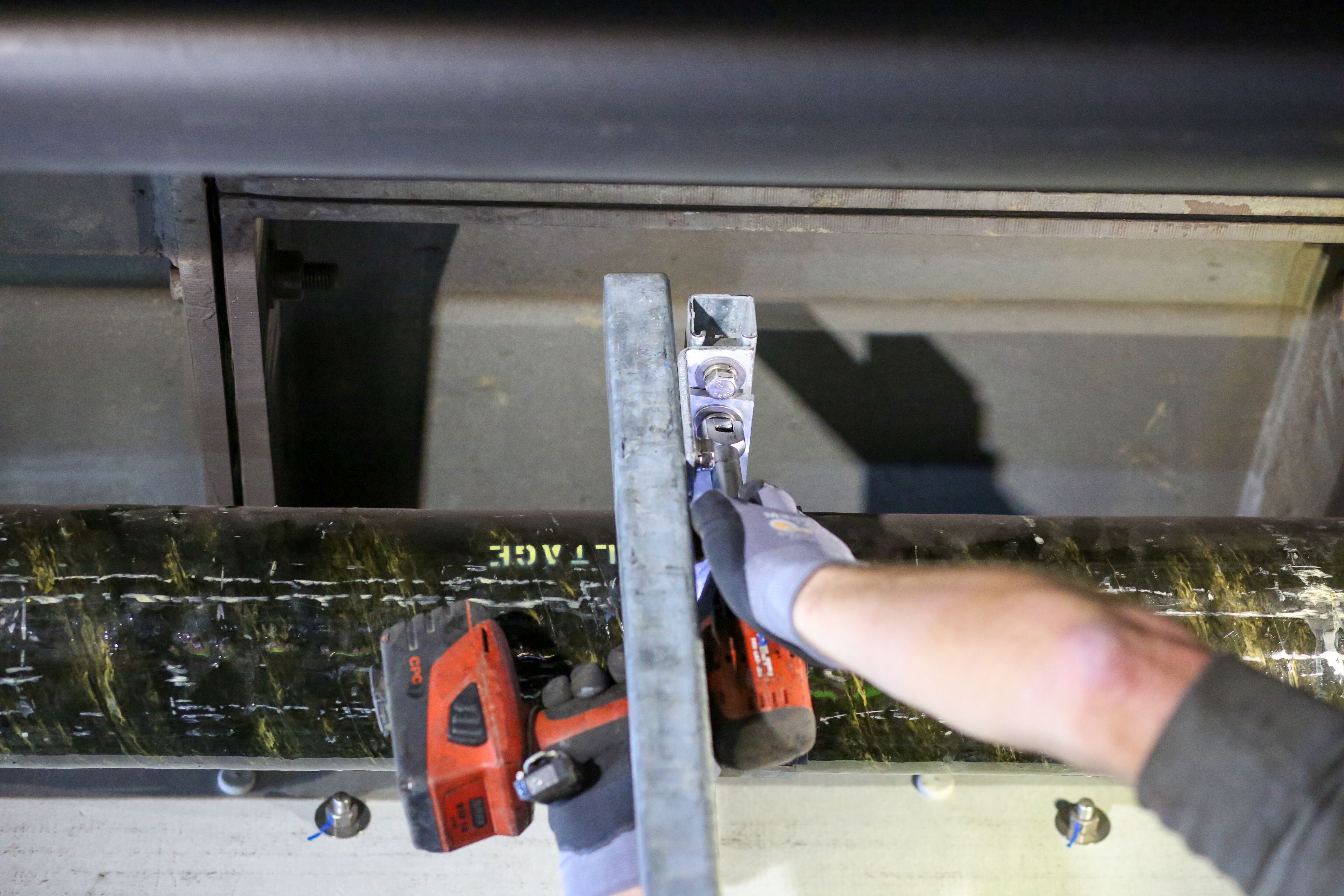 A journeyman electrician attaches conduit to the steel ring of the tunnel using high-strength structural steel.