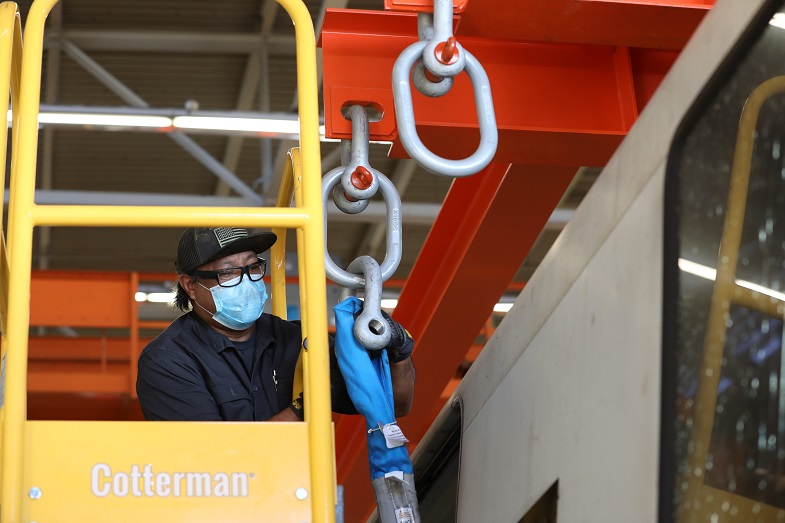 A worker prepares a strap that will be used to hoist the train car 