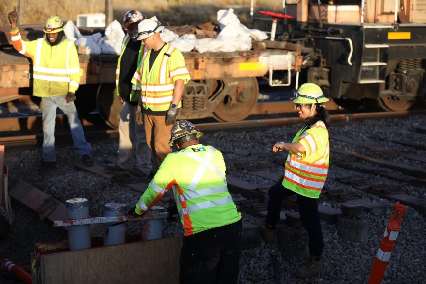 Thu Nguyen on the right laughs with four track workers as they work on a trackway