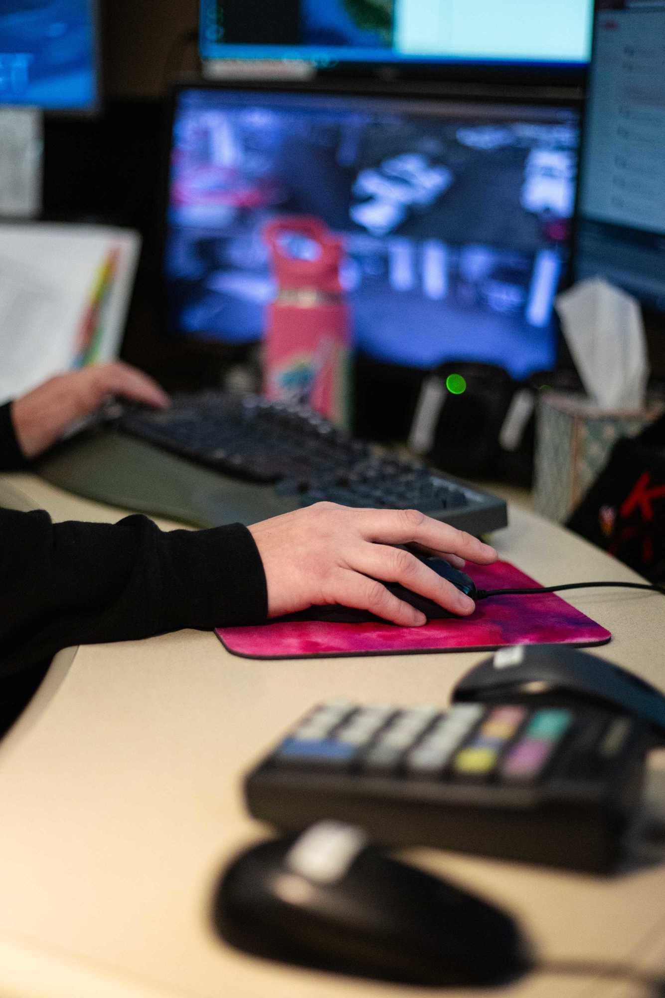 Hand on a mouse with two other mice and a computer screen