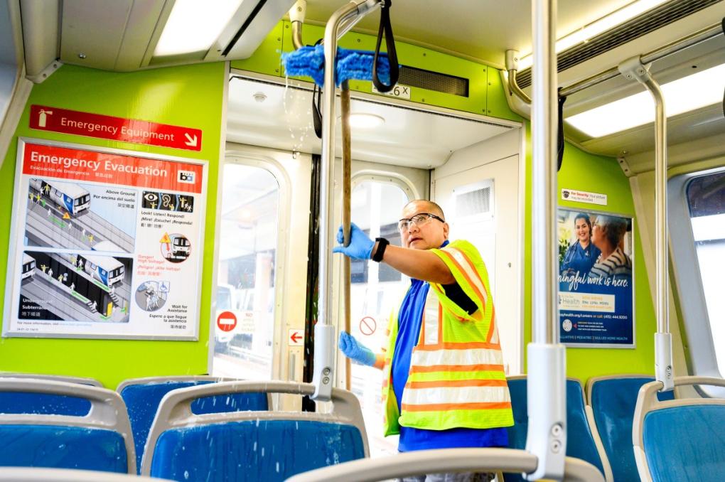 Train car cleaner Rodelio Correa scrubs the ceiling and poles with hot water and disinfectant soap during a thorough clean.  