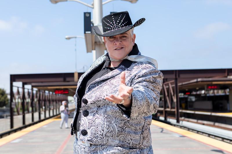 Elvis Herselvis depcited at MacArthur Station in a silver suit with her hand reaching out