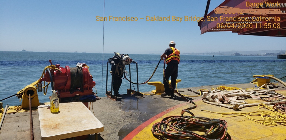 Diver stepping off barge into the bay as part of cable installation operations near the TBT.