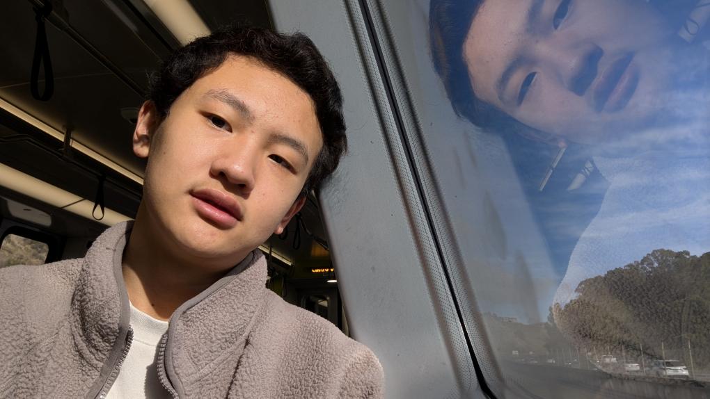 Enzo Wu in a selfie on a train with his face reflected in the glass